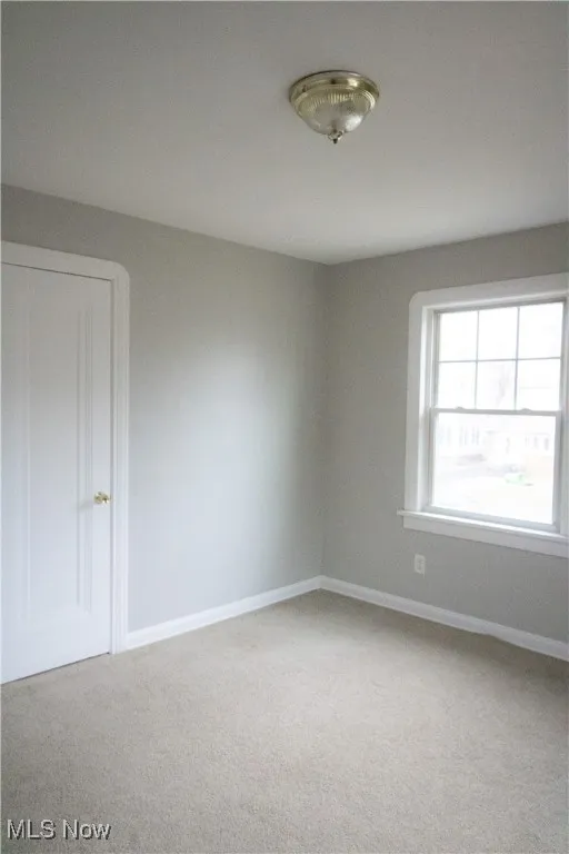 Carpeted empty room featuring baseboards
