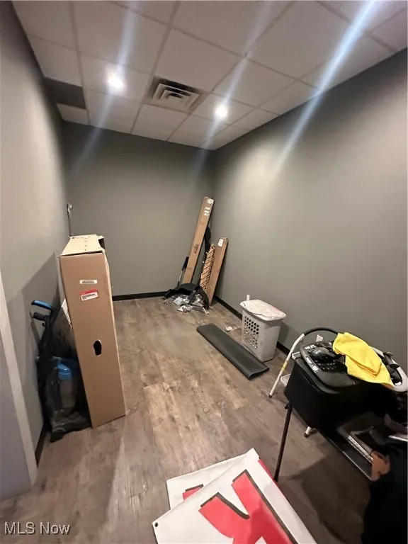 Miscellaneous room with a drop ceiling and wood-type flooring