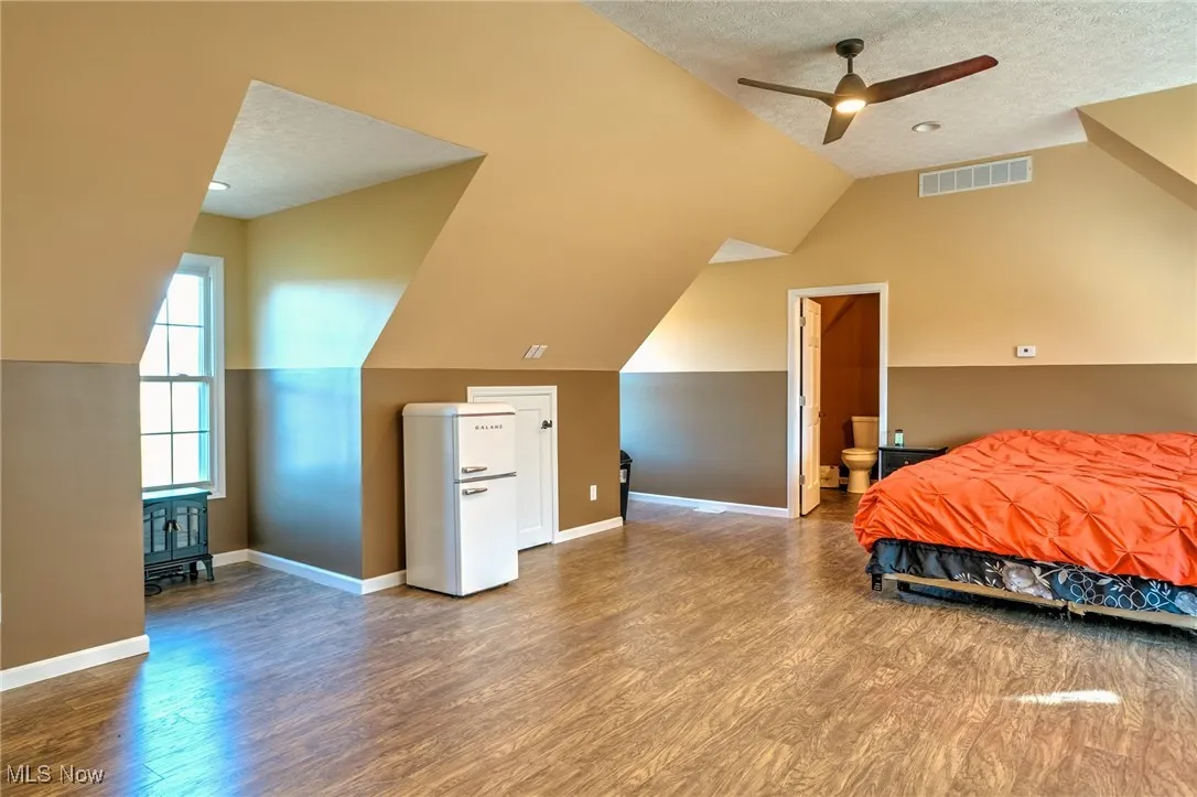 Bedroom featuring visible vents, wood finished floors, lofted ceiling, and a textured ceiling