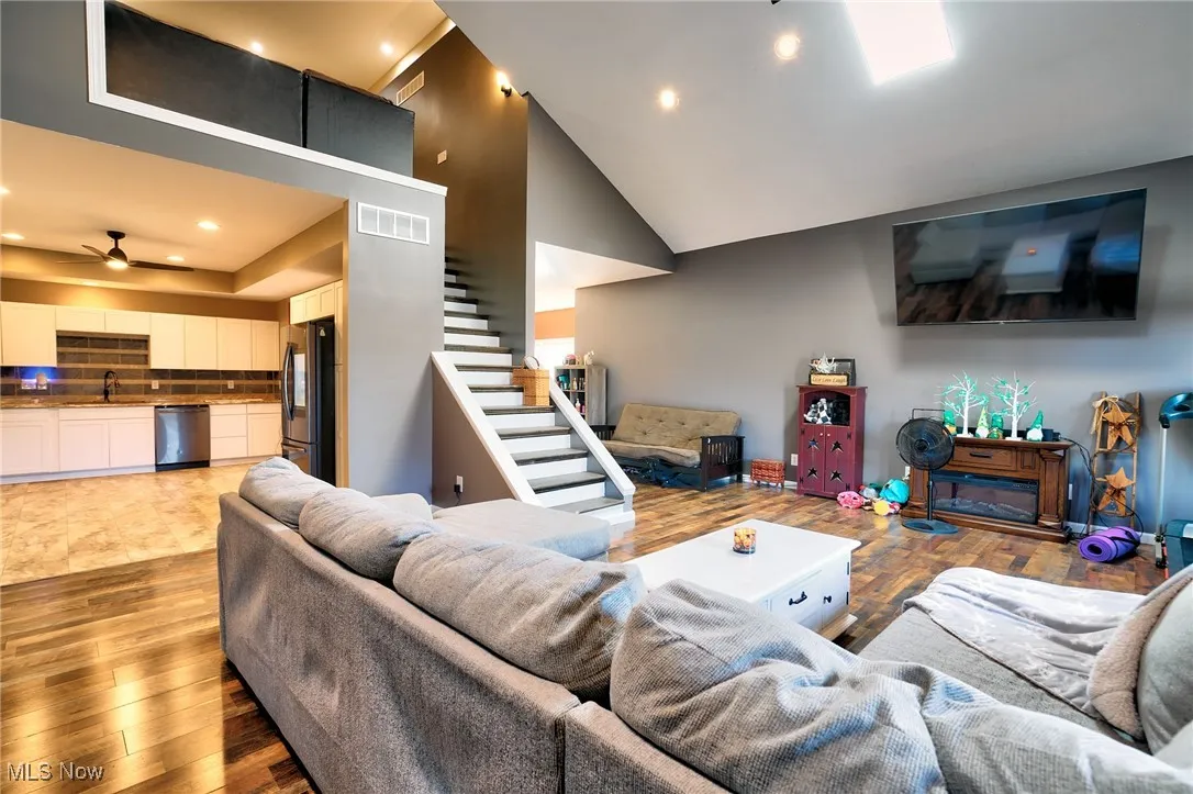 Living room featuring stairway, wood finished floors, visible vents, ceiling fan, and recessed lighting