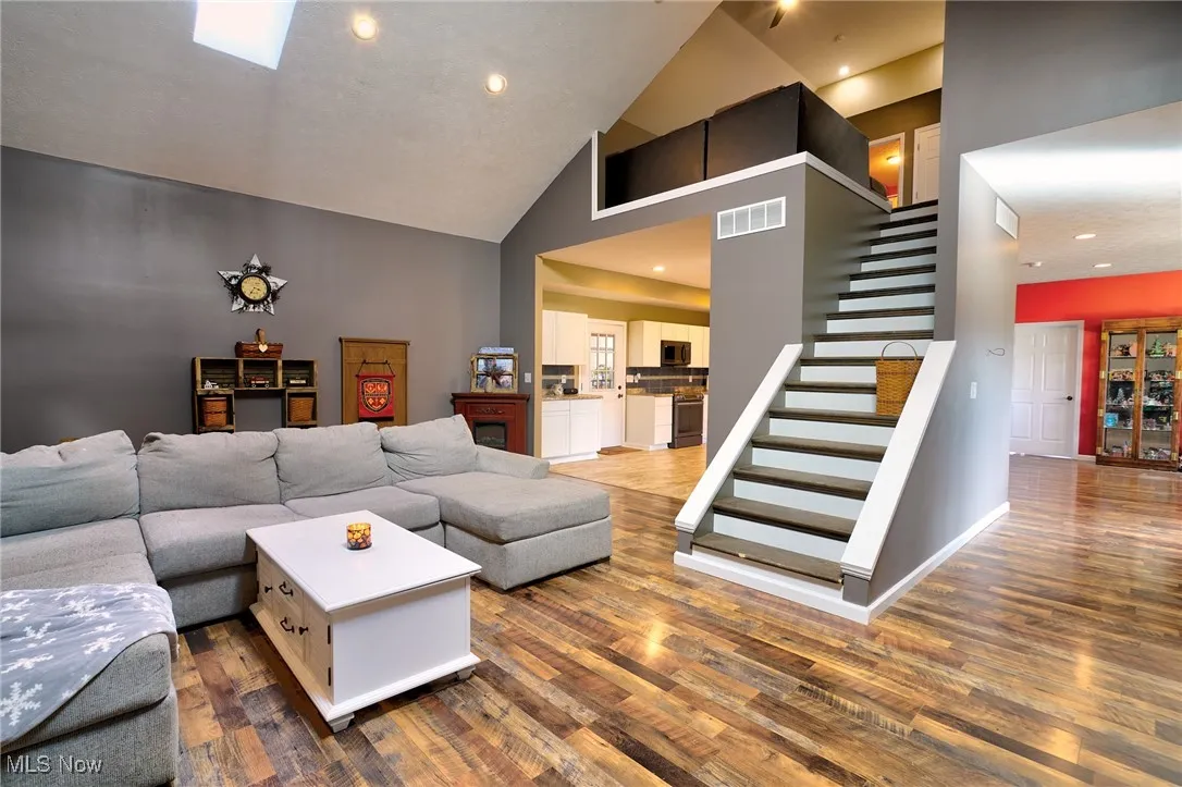 Living area featuring visible vents, stairway, and wood finished floors