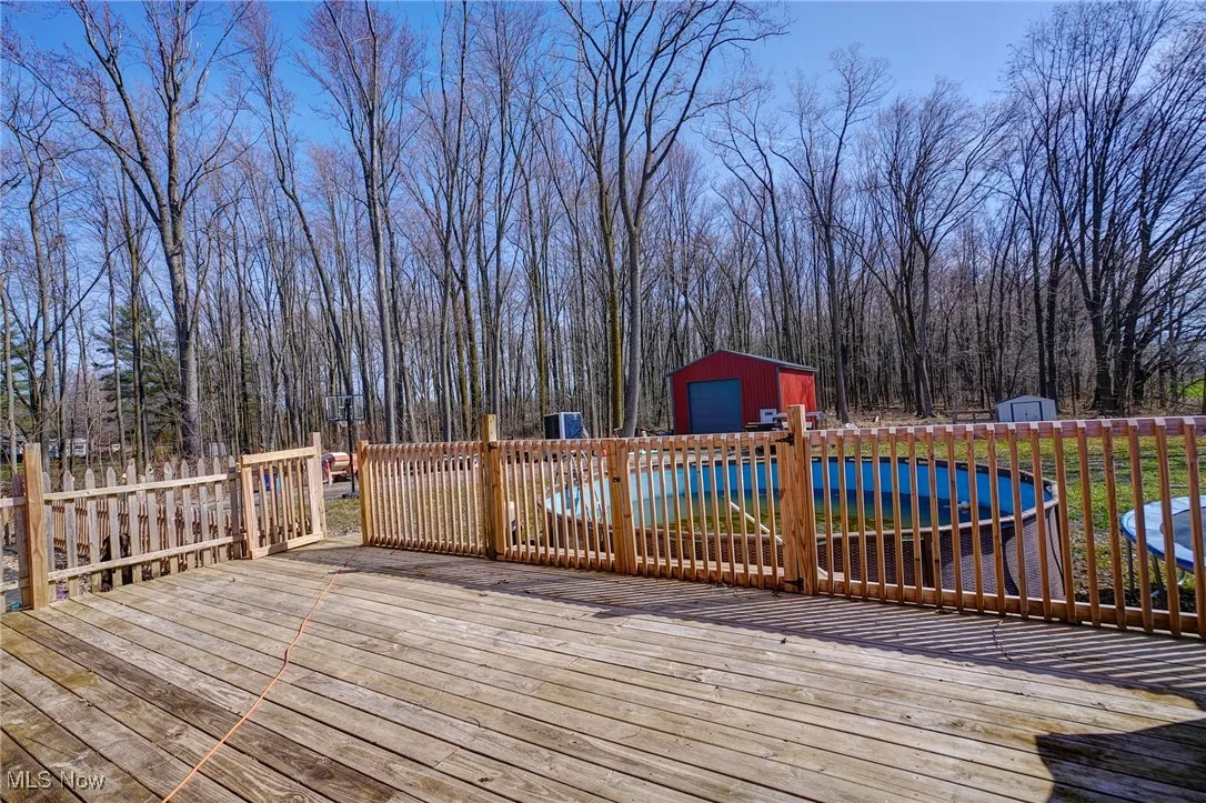 Wooden terrace with a shed, an outdoor structure, and a fenced in pool