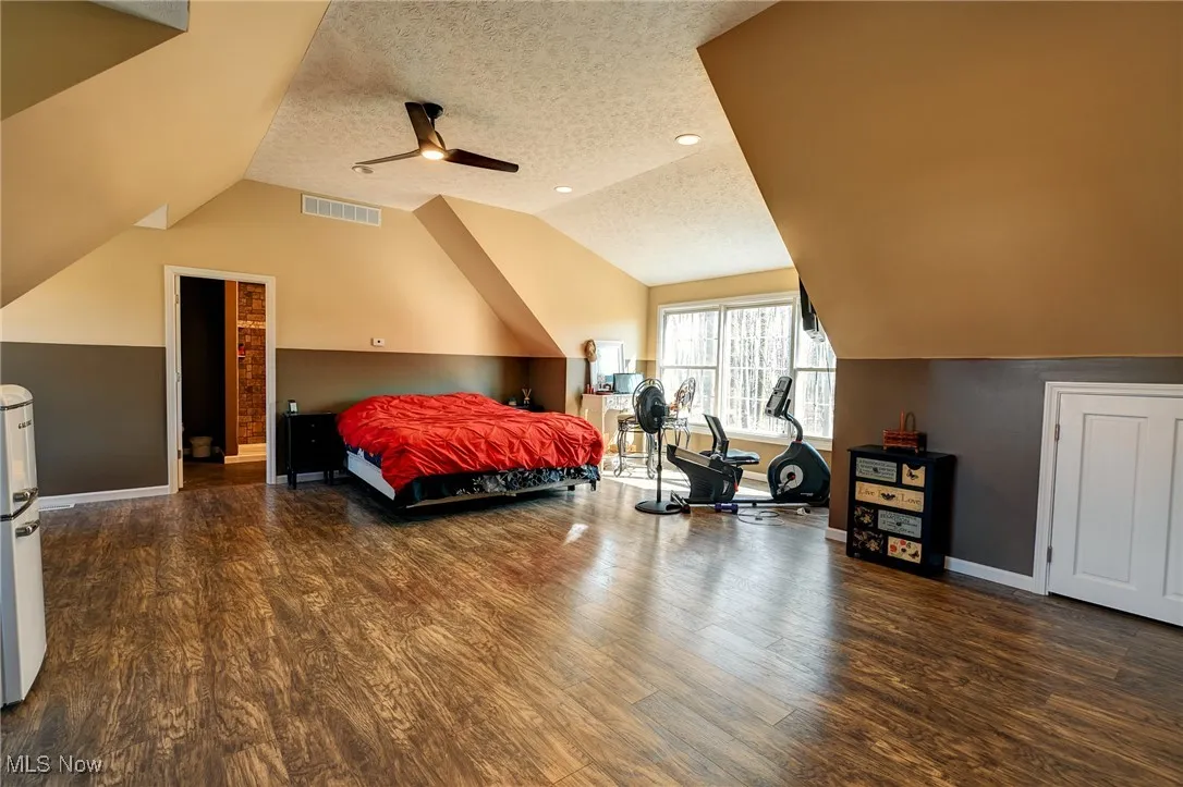 Bedroom with lofted ceiling, wood finished floors, and a textured ceiling