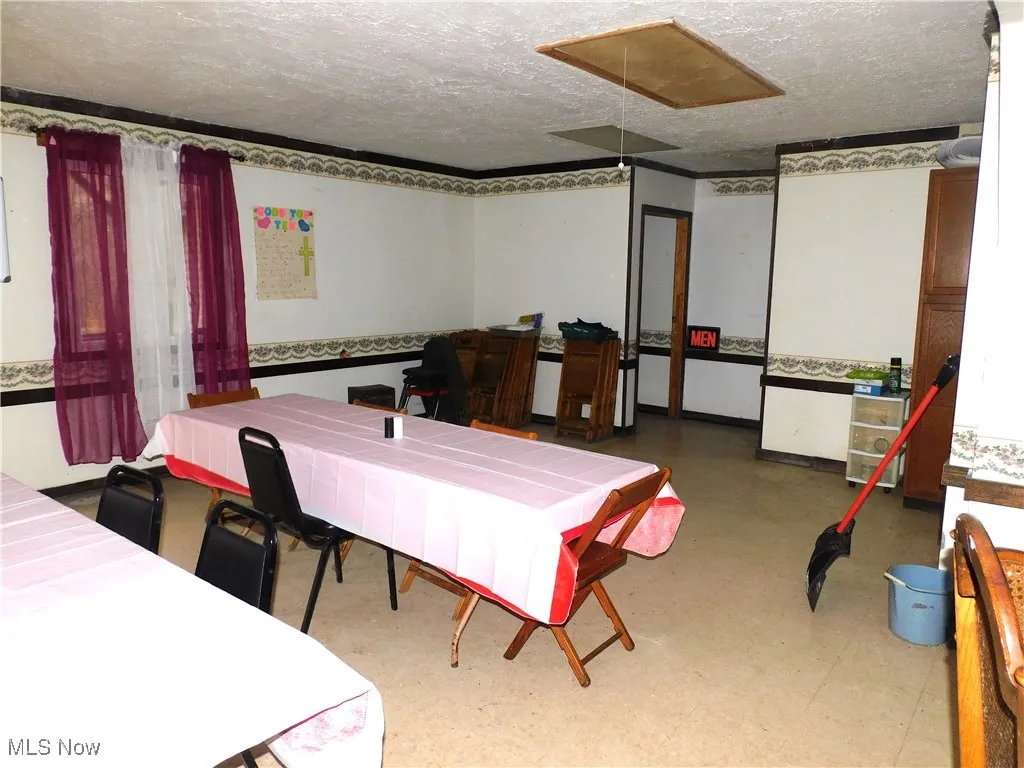 Dining area featuring a textured ceiling, tile patterned floors, and attic access