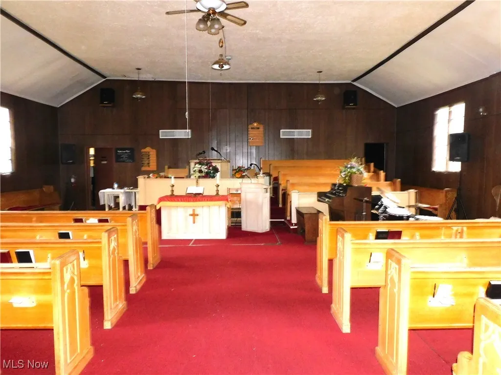 Game room with visible vents, wood walls, vaulted ceiling, and a ceiling fan