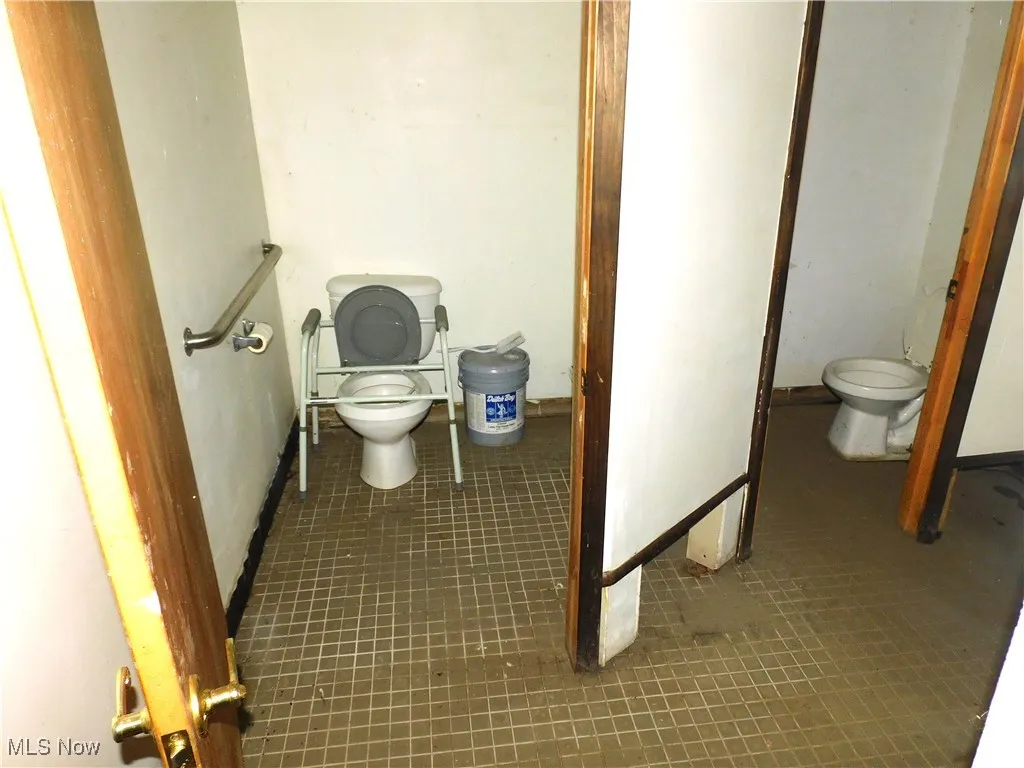 Bathroom featuring toilet, tile patterned floors, and baseboards