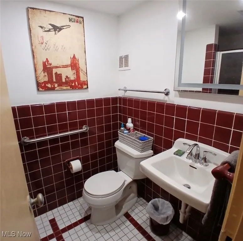 Bathroom with tile patterned flooring, tile walls, and wainscoting