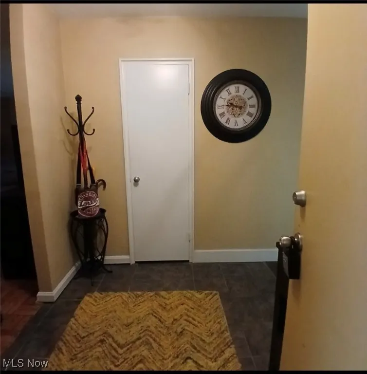 Corridor with baseboards and dark tile patterned flooring