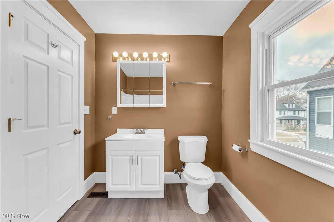 Bathroom with toilet, vanity, baseboards, and wood finished floors