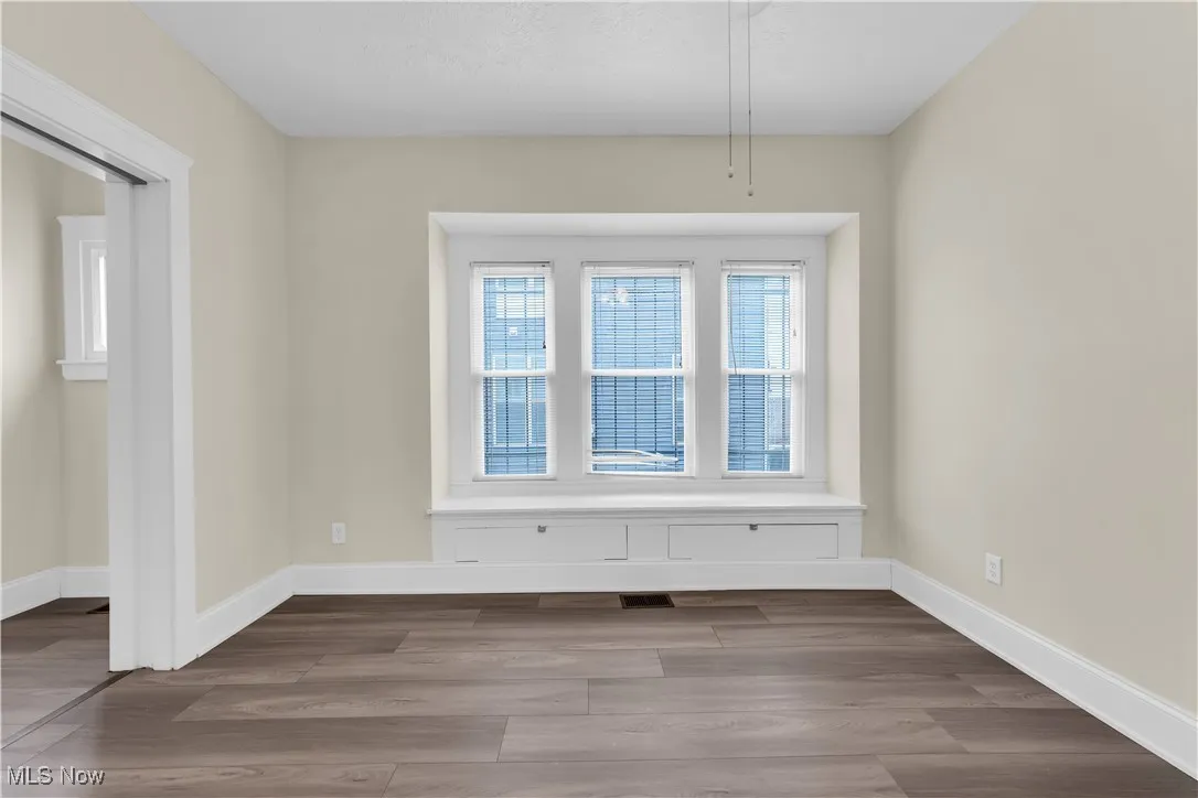 Unfurnished room featuring baseboards, visible vents, and wood finished floors