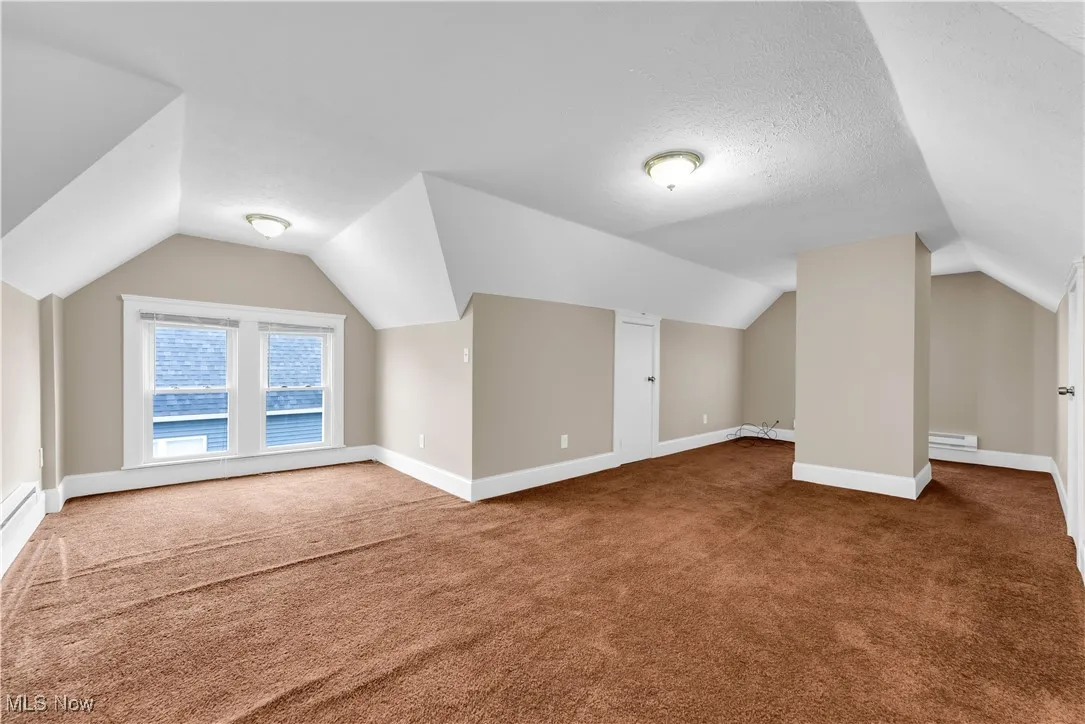 Bonus room with baseboards, vaulted ceiling, carpet floors, and a textured ceiling