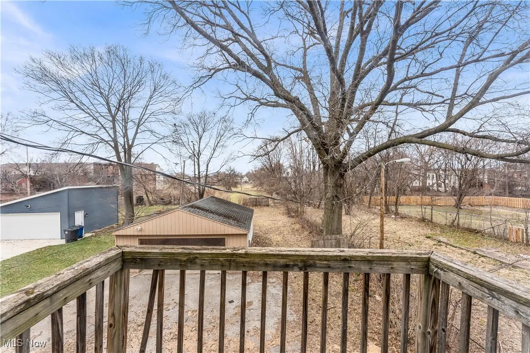 Wooden terrace featuring an outbuilding, fence, and a detached garage