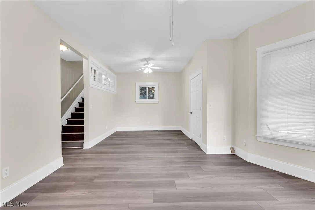 Spare room featuring wood finished floors, baseboards, stairway, and ceiling fan