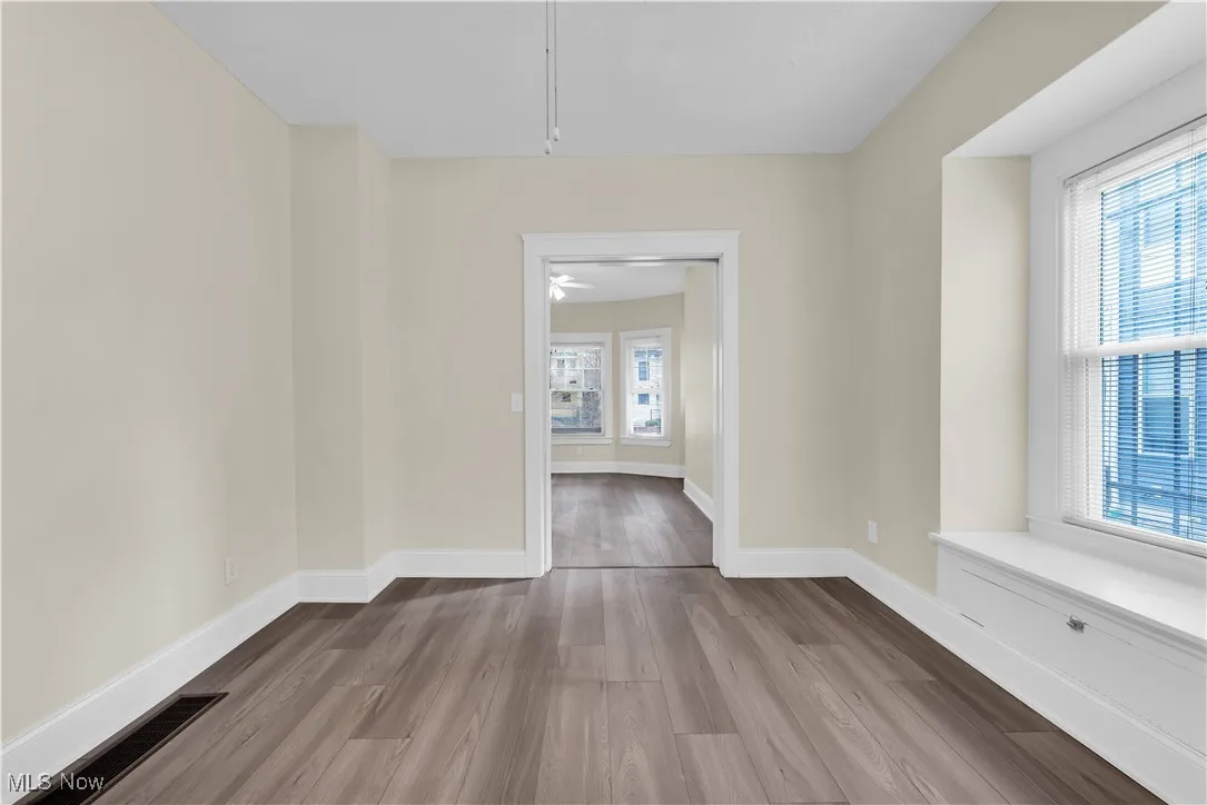 Empty room with visible vents, baseboards, a healthy amount of sunlight, and wood finished floors