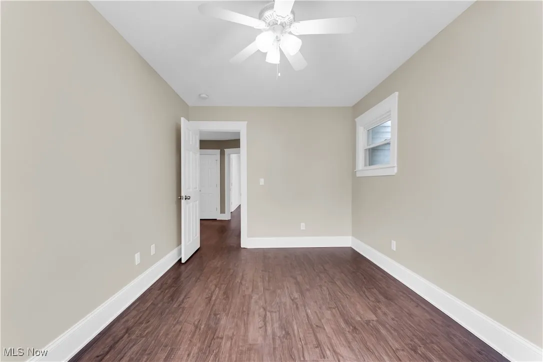 Spare room featuring baseboards, ceiling fan, and dark wood-style flooring