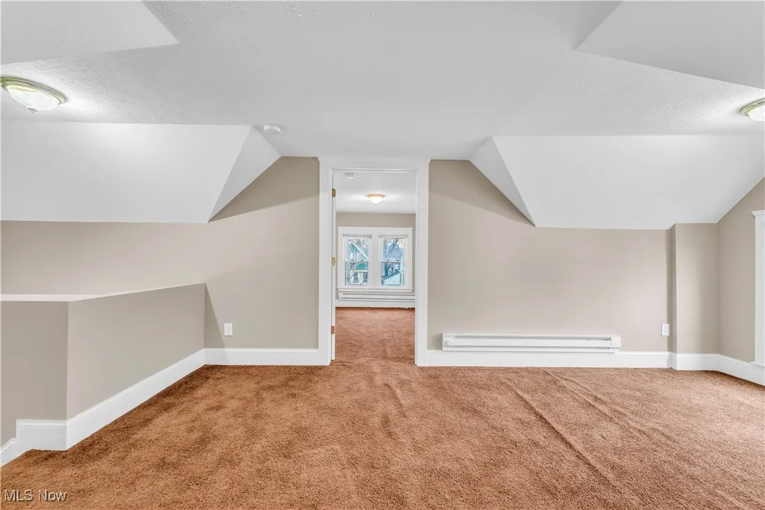 Bonus room featuring baseboards, carpet floors, vaulted ceiling, and a baseboard heating unit