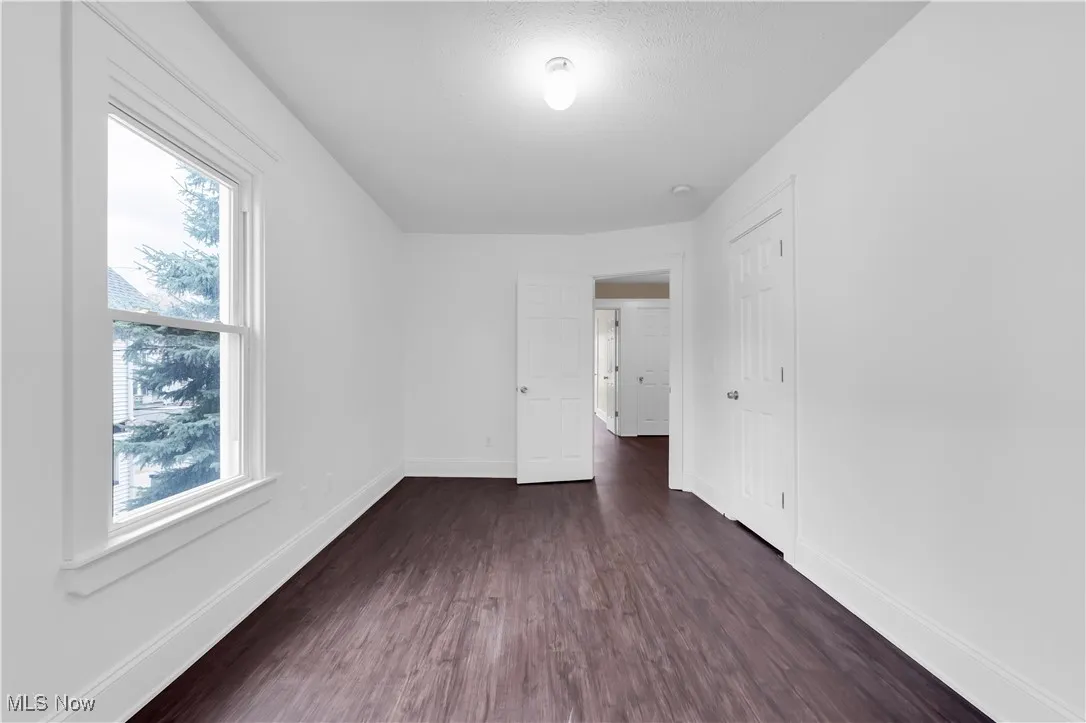 Empty room with baseboards and dark wood finished floors