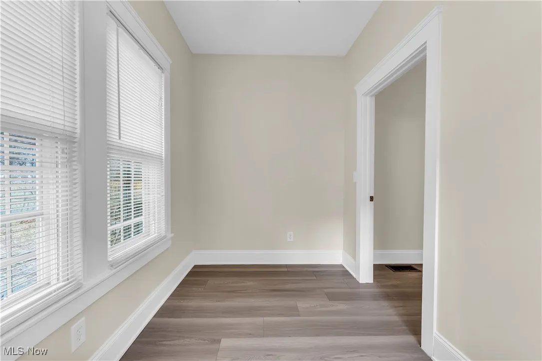 Unfurnished room featuring baseboards, visible vents, and wood finished floors