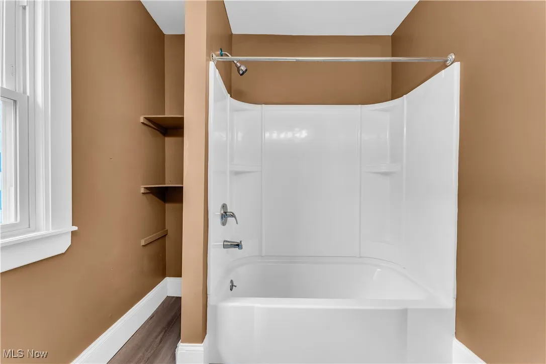 Full bathroom with baseboards, shower / tub combination, and wood finished floors