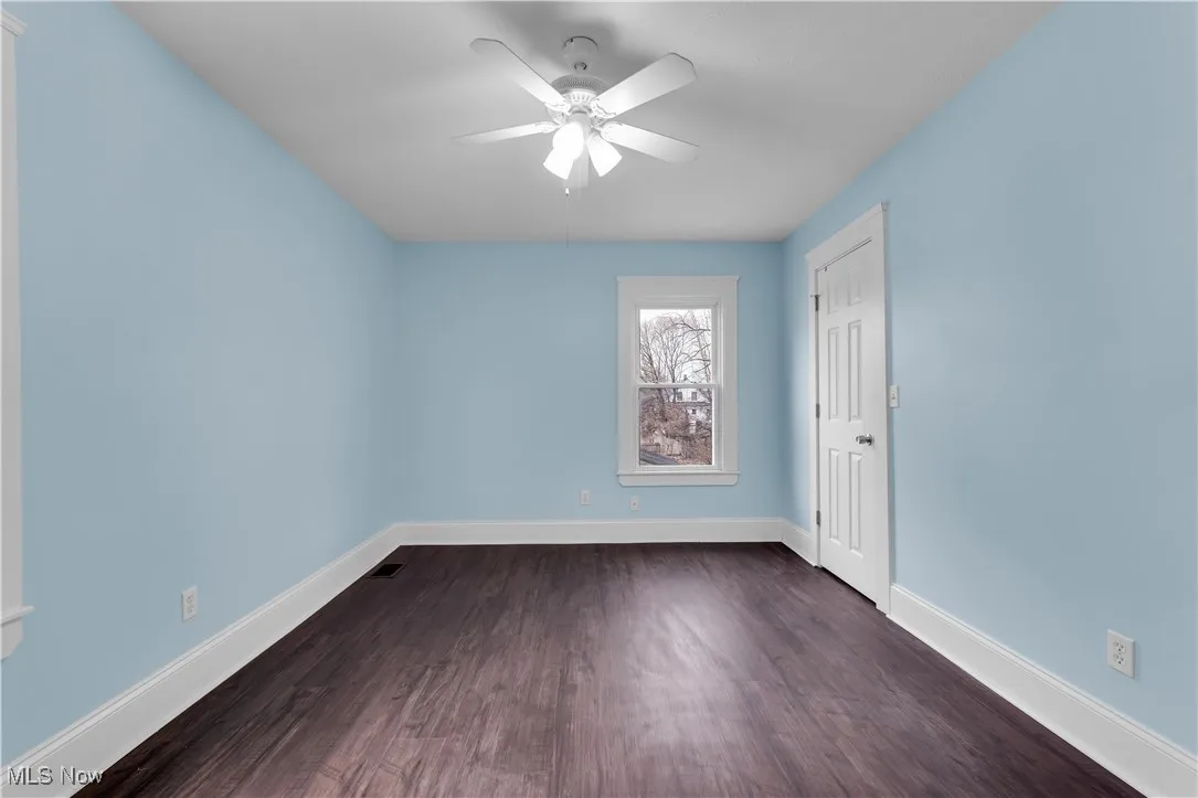 Empty room featuring baseboards, ceiling fan, and dark wood-type flooring