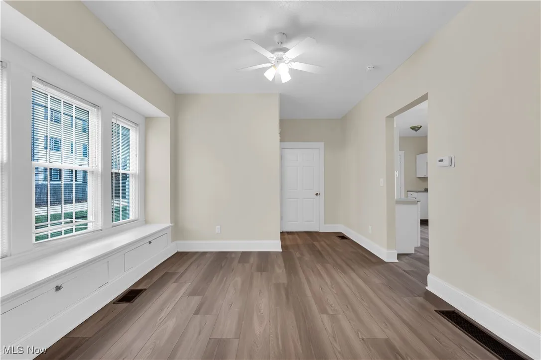 Spare room featuring a ceiling fan, visible vents, baseboards, and wood finished floors