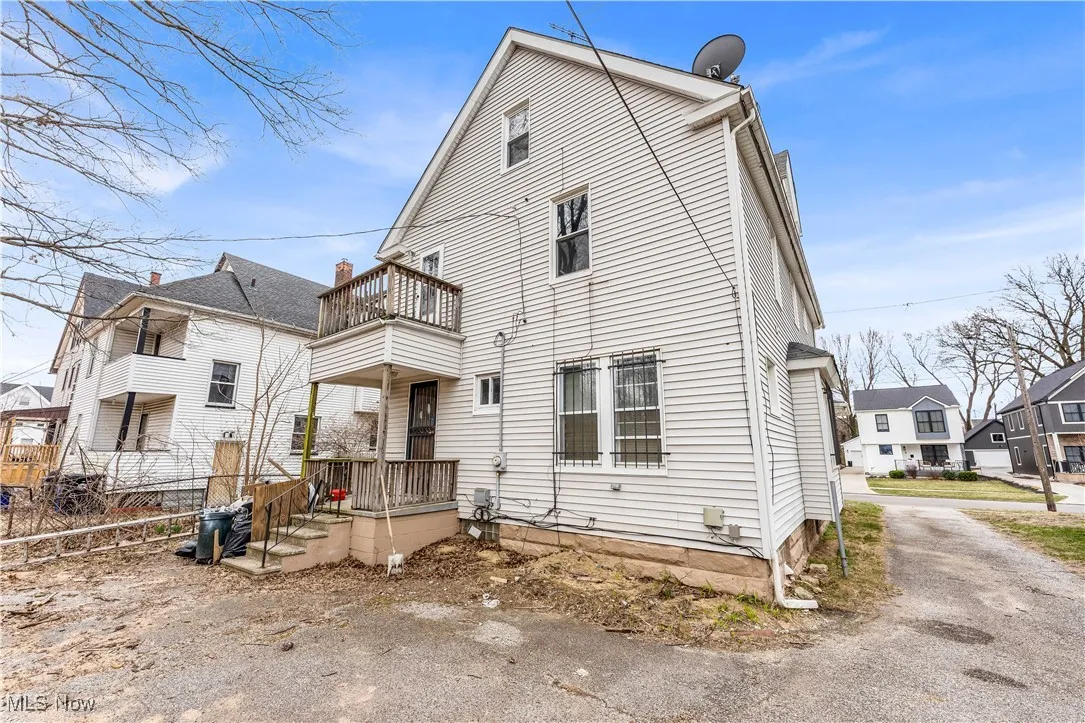 Rear view of house featuring a balcony, driveway, and a residential view