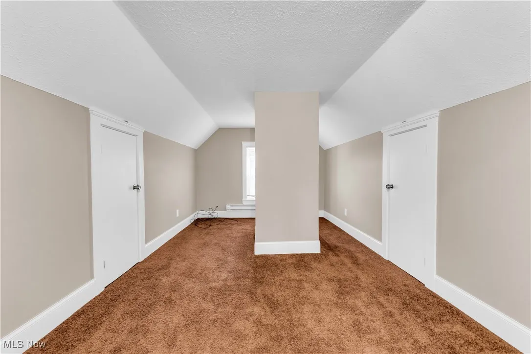 Additional living space with baseboards, carpet flooring, a textured ceiling, and vaulted ceiling