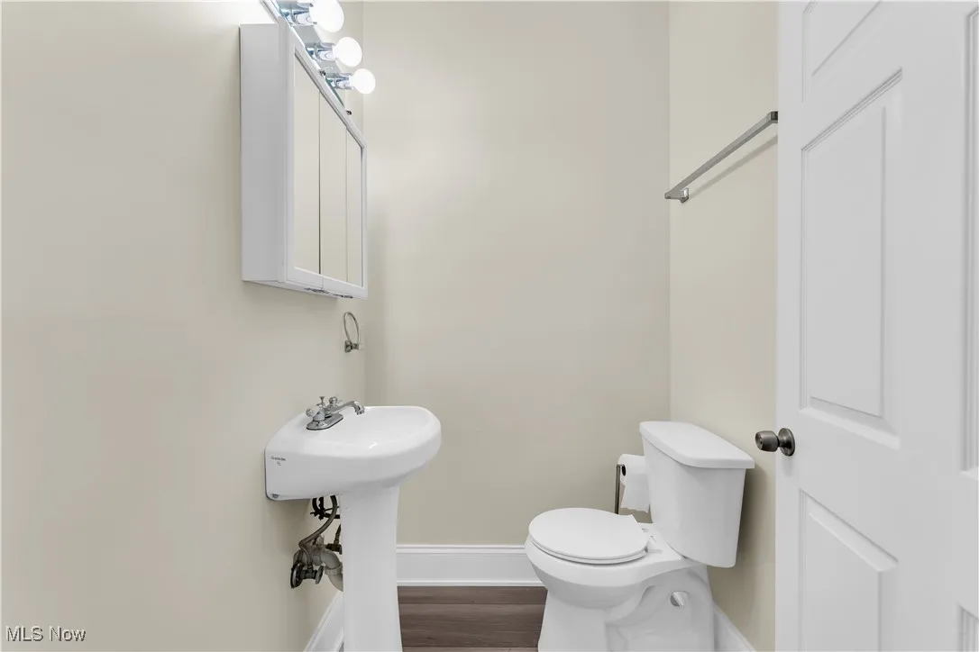 Bathroom with toilet, baseboards, and wood finished floors