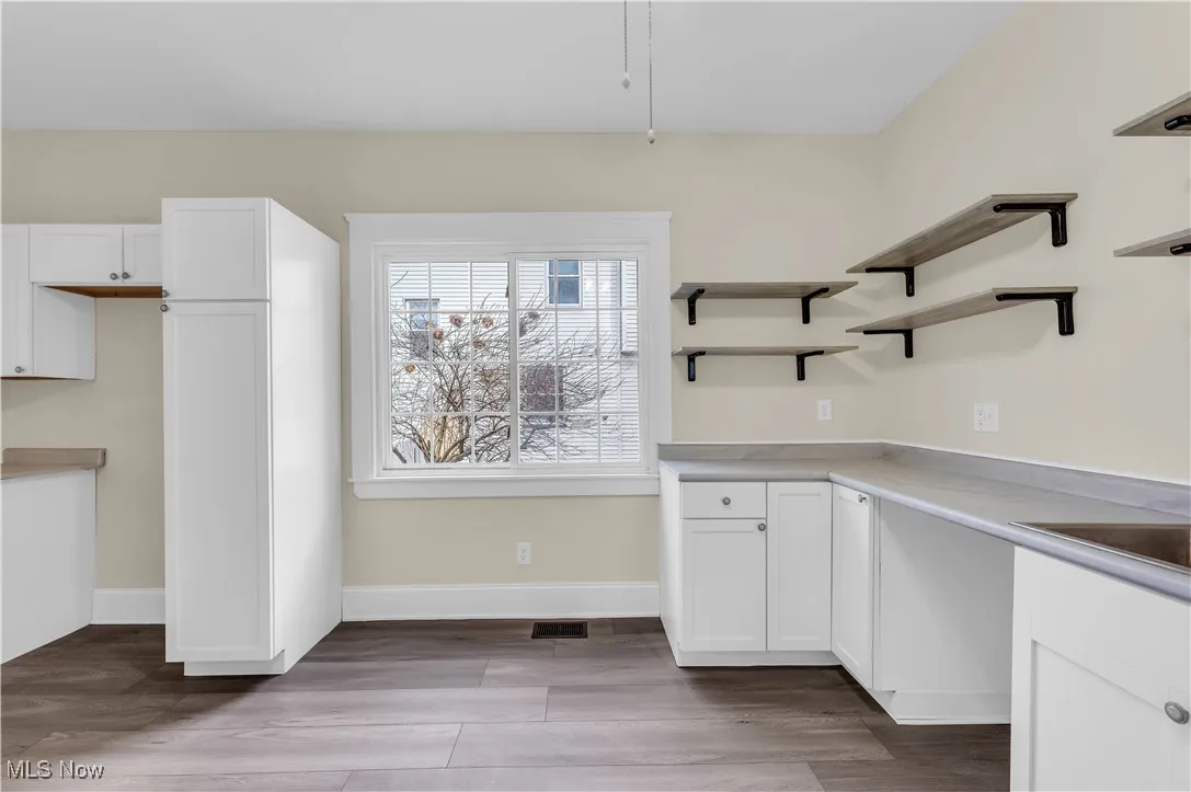 Kitchen featuring white cabinetry, light countertops, baseboards, visible vents, and wood finished floors