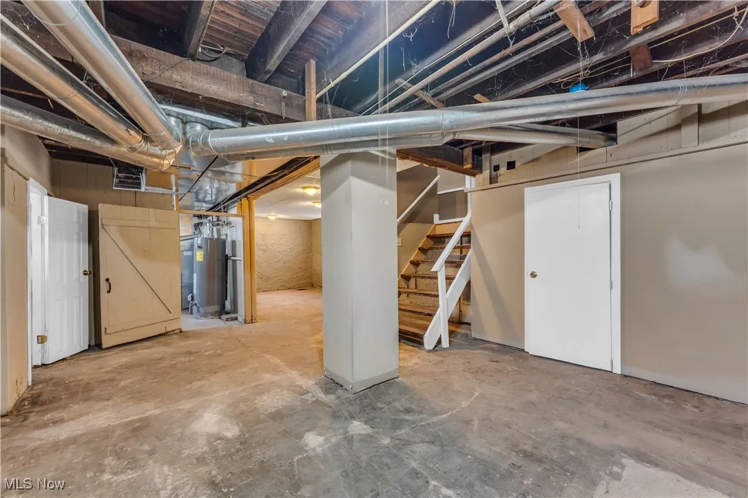 Unfinished below grade area with water heater, stairs, and visible vents