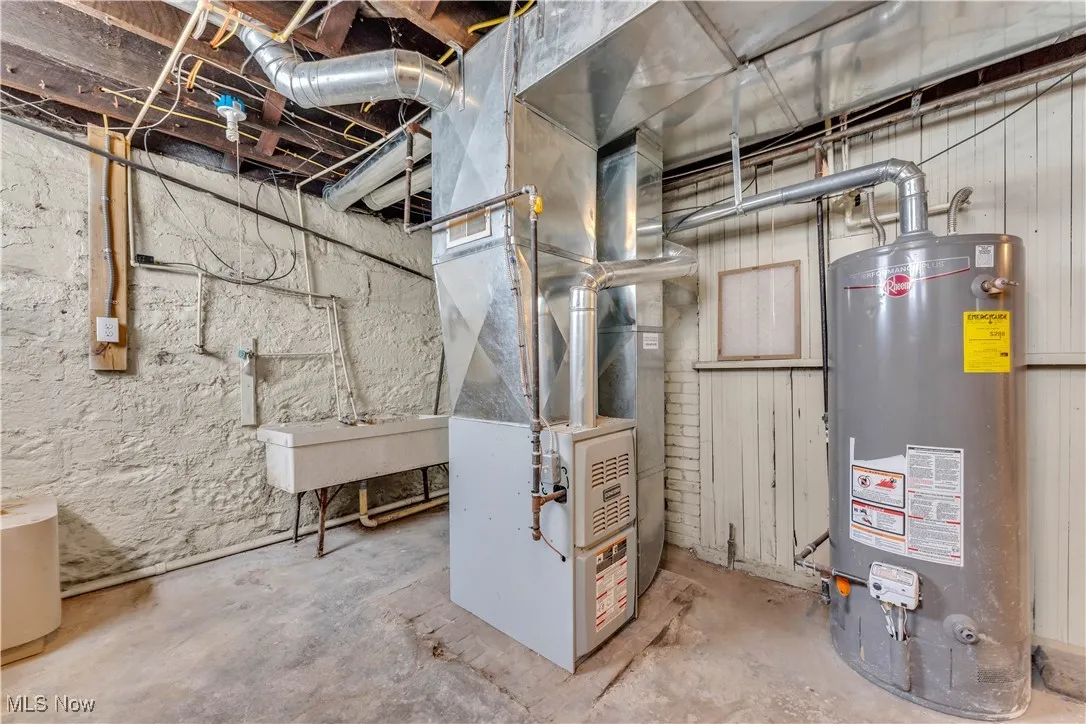 Utility room featuring a sink, heating unit, and gas water heater