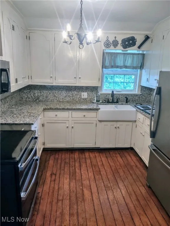 Kitchen featuring white cabinets, a sink, stainless steel appliances, and decorative backsplash