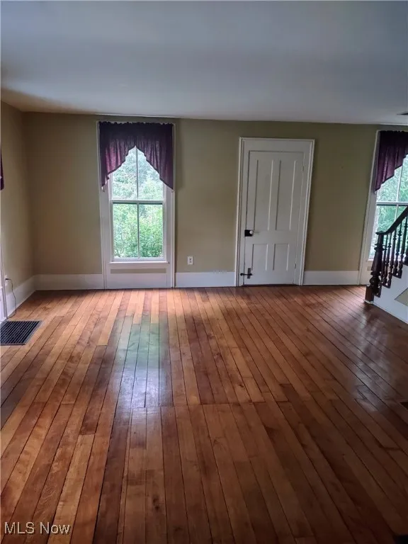 Spare room featuring baseboards, visible vents, and hardwood / wood-style flooring
