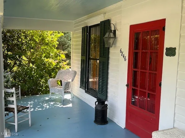 Entrance to property featuring covered porch and concrete block siding