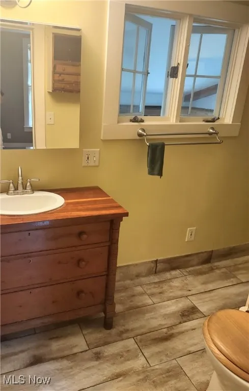 Half bathroom featuring toilet, vanity, and wood finished floors