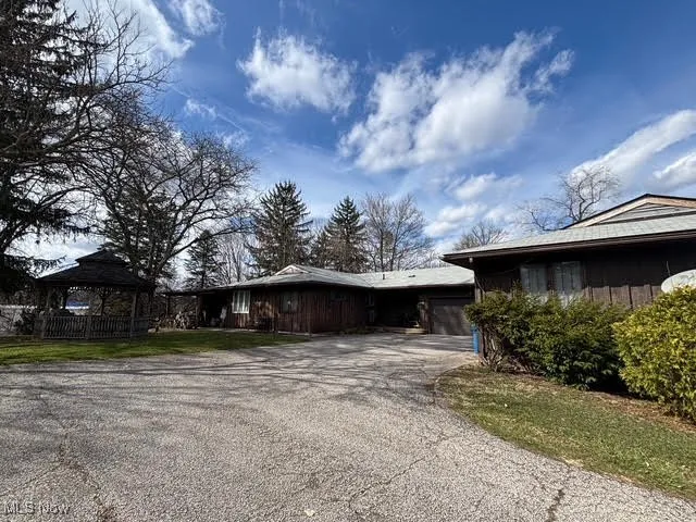 View of home's exterior with driveway, a garage, and a gazebo