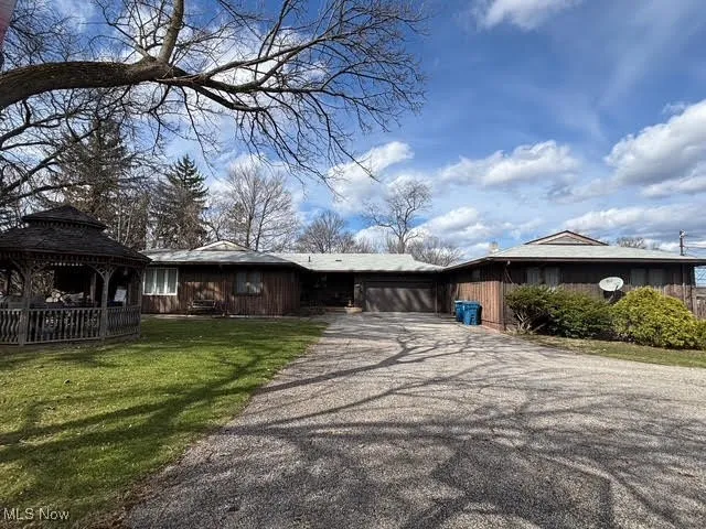 View of side of house with driveway, an attached garage, a gazebo, and a front yard