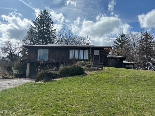 View of side facade with a front yard, an attached garage, and aphalt driveway