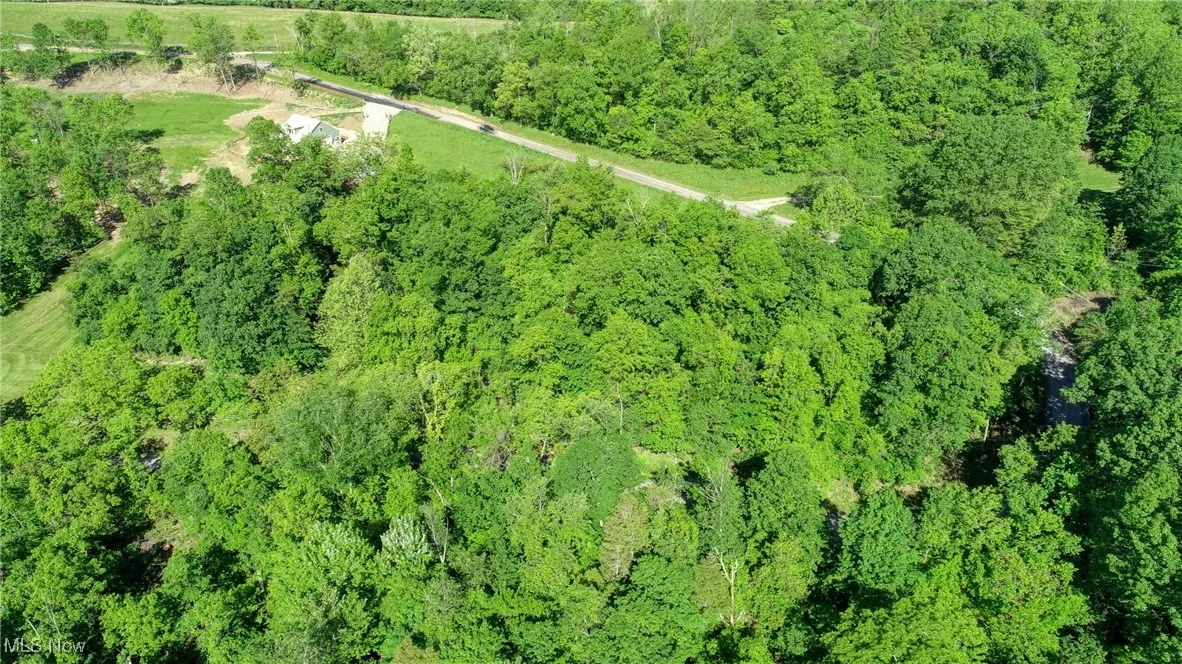 Aerial view of property and surrounding area with a heavily wooded area