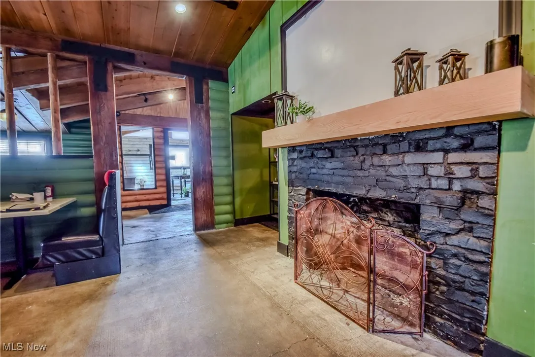 Living room featuring a fireplace, lofted ceiling, log walls, and wood ceiling