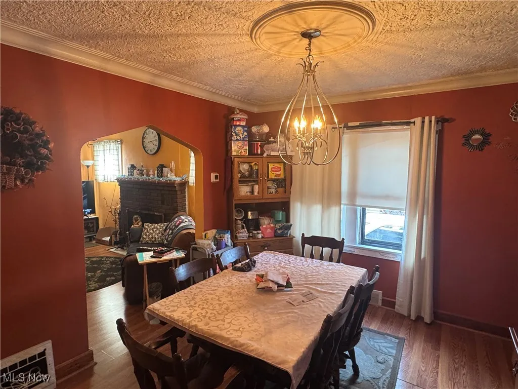 Dining space featuring ornamental molding, visible vents, an inviting chandelier, and wood finished floors