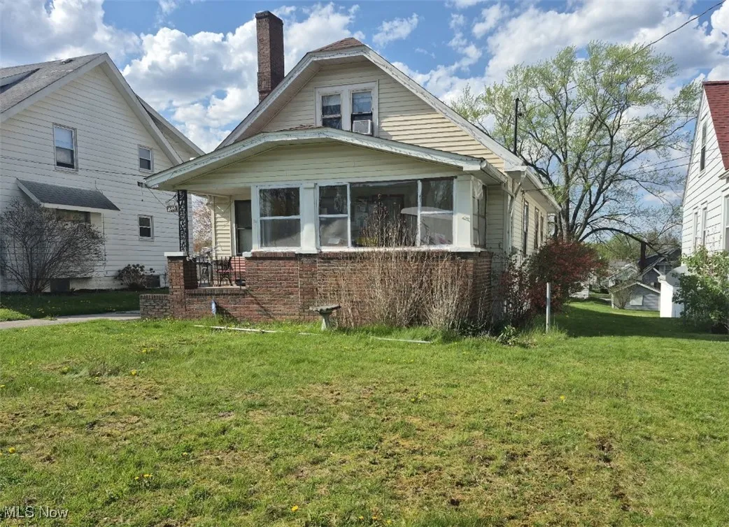 View of front facade with a front lawn, brick siding, and a chimney