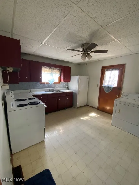 Kitchen with light floors, fridge, washer / dryer, and range