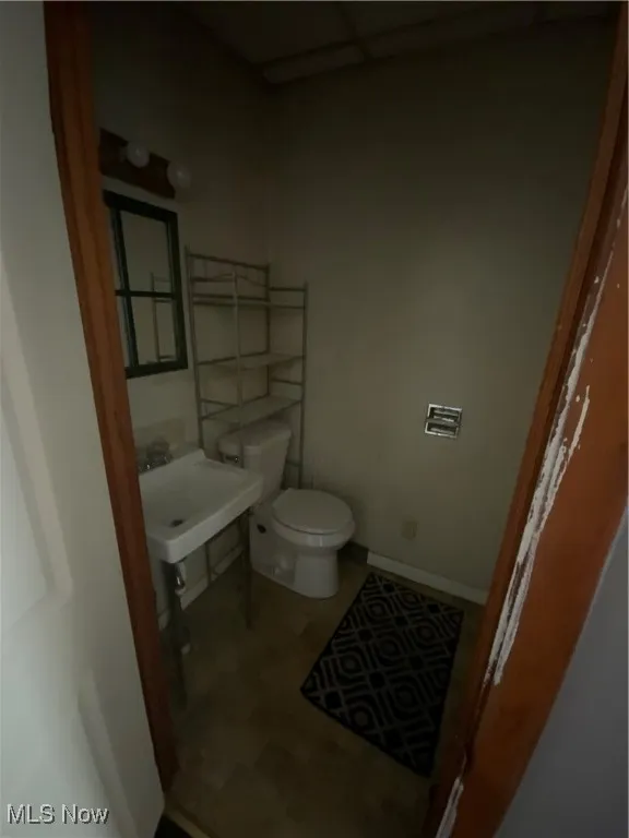 Half bath featuring baseboards, toilet, and a sink