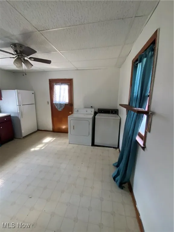 Clothes washing area featuring light floors, laundry area, baseboards, independent washer and dryer, and ceiling fan
