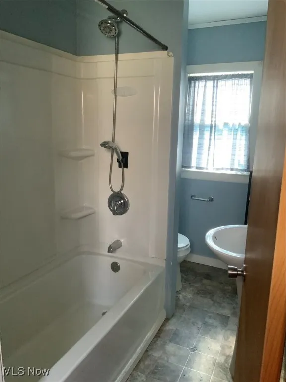 Full bath with washtub / shower combination, baseboards, toilet, and ornamental molding