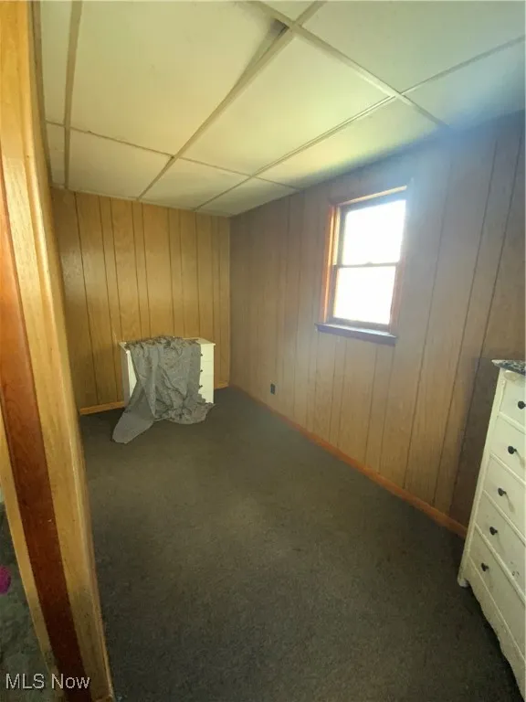 Unfurnished bedroom featuring carpet floors and wood walls