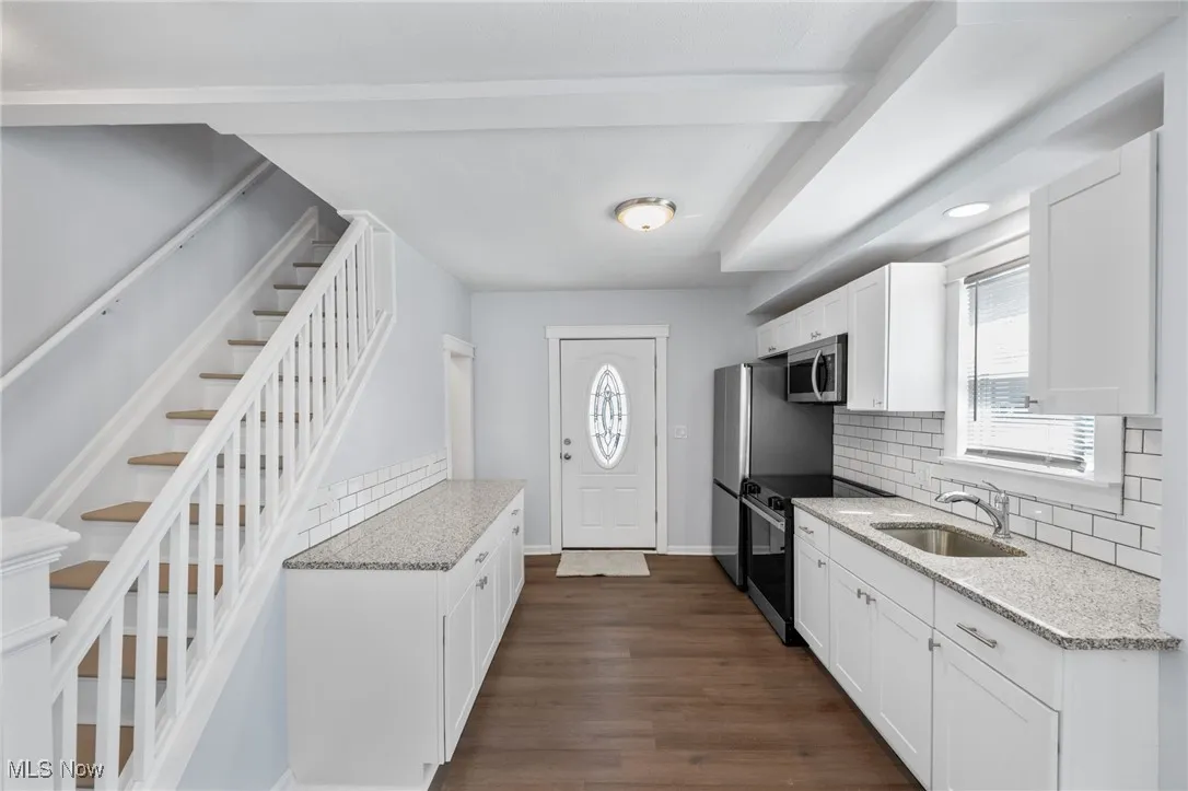 Kitchen with stainless steel appliances, backsplash, a healthy amount of sunlight, a sink, and white cabinetry