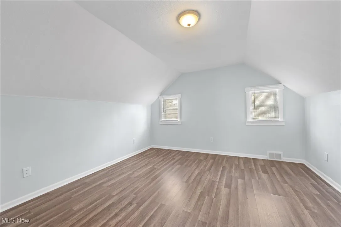 Bedroom  featuring baseboards, lofted ceiling, and wood style floors