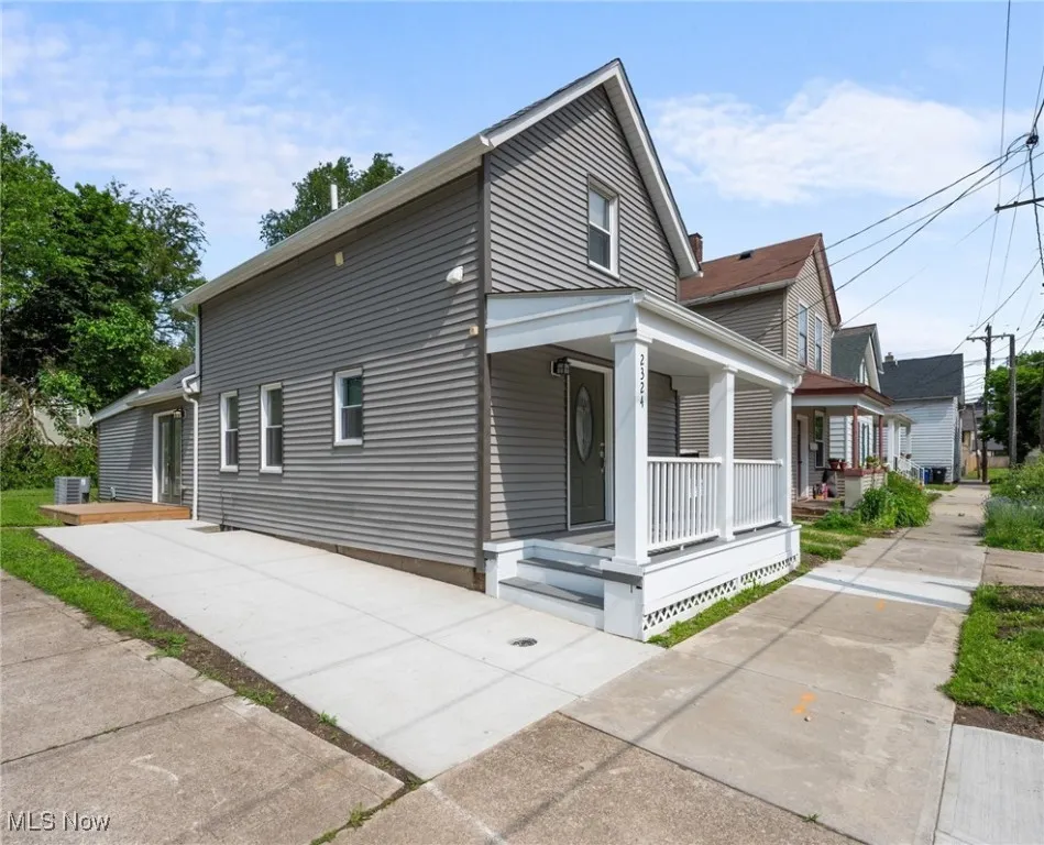 View of side of property featuring a porch and concrete driveway